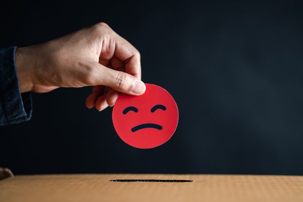 A hand holding an unhappy emoji