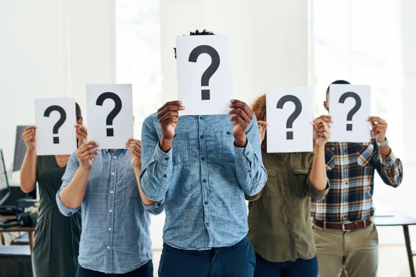 Several people holding papers with question marks in front of their faces